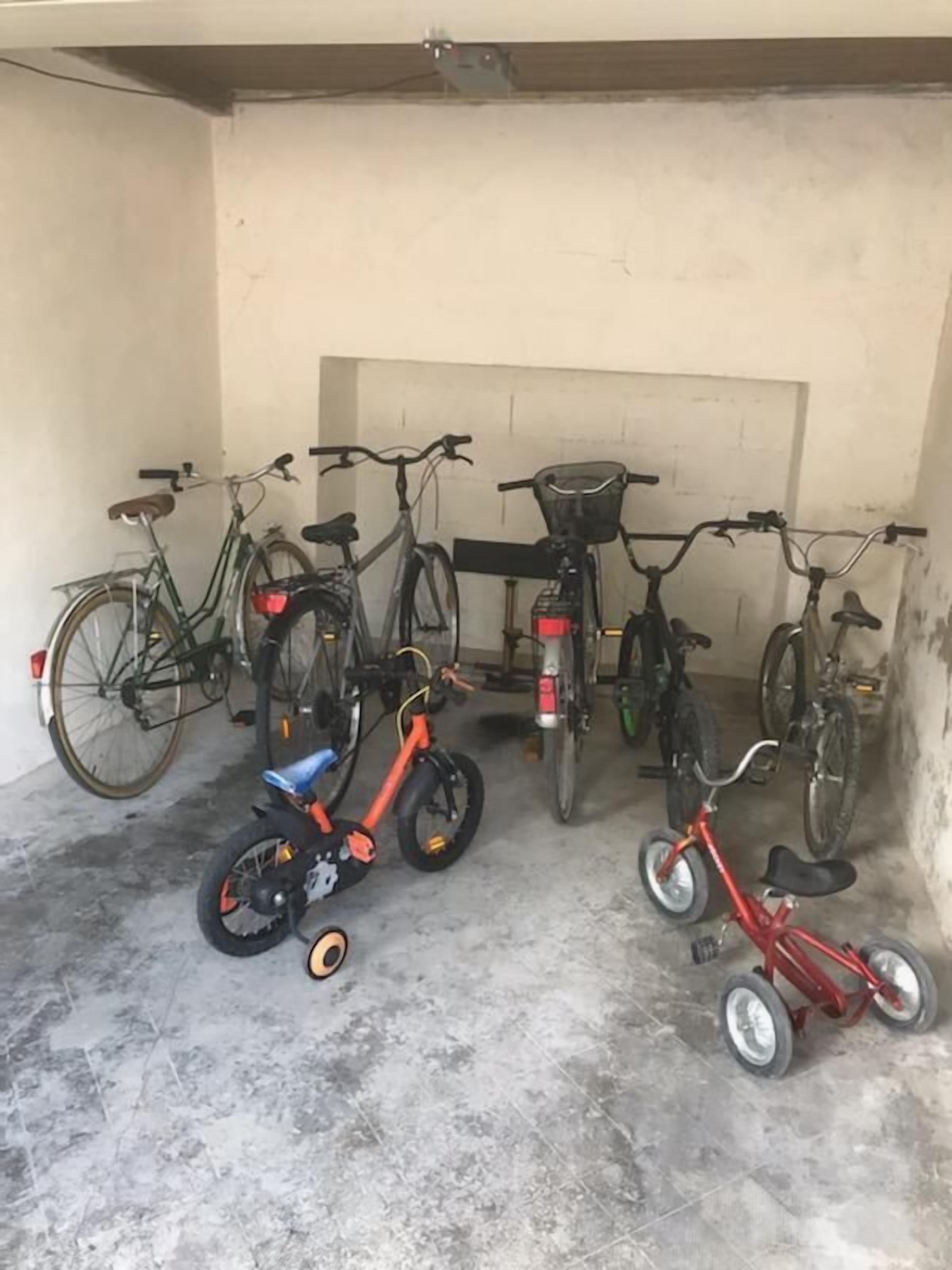 Een garage met fietsen en een driewieler.