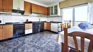 Une cuisine avec des meubles de rangement en bois, une cuisinière et un coin repas comprenant une table et des chaises.