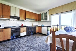 Une cuisine avec des meubles de rangement en bois, une cuisinière et un coin repas comprenant une table et des chaises.