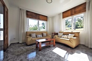 A living room with two sofas, a coffee table, and large windows with curtains.