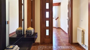 Un pasillo con baldosas estampadas, una puerta de madera con paneles de vidrio y un radiador en la pared.