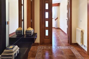 A hallway with patterned tiles, a wooden door with glass panels, and a radiator on the wall.