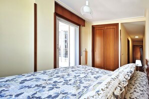 Ein Schlafzimmer mit einem Bett, einem Holzschrank, einer Tür und einem Fenster.