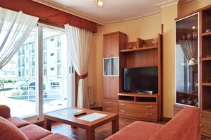 A living room with a TV, wooden cabinets, a sofa, and a table.