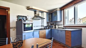 Una cocina con armarios azules, una mesa de comedor de madera y un ventanal.