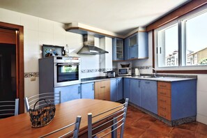 Eine Küche mit blauen Schränken, einem Holztisch und einem Fenster.