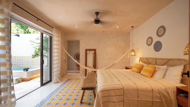 A bedroom with a large bed, a hammock, a view of a pool, and a tiled floor. - Casa Copán: Colonial charm in downtown Merida (Mérida)