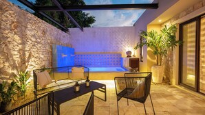 An outdoor patio with a stone wall, a blue-lit wall, and a seating area with chairs and a table. - Casa Copán: Colonial charm in downtown Merida (Mérida)