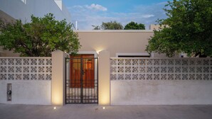 A gated entrance with a wooden door, white walls, and decorative lattice panels. - Casa Copán: Colonial charm in downtown Merida (Mérida)