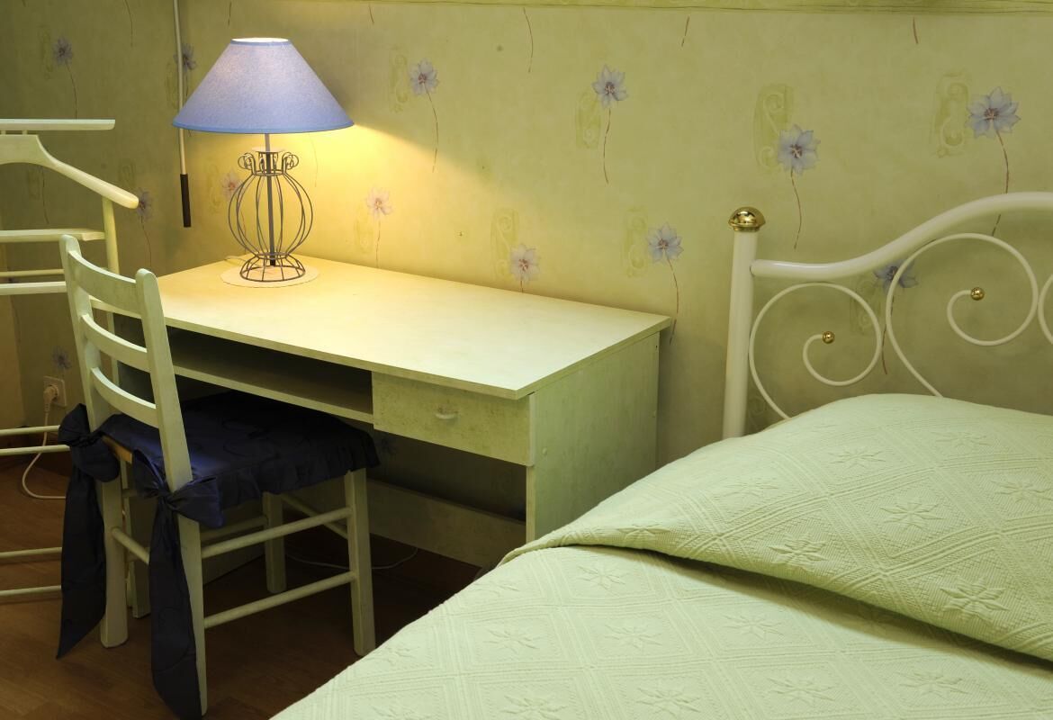 Ein Zimmer mit einem Bett, einem Schreibtisch mit Lampe und einem Stuhl.