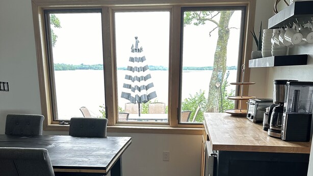 Een moderne keuken met een groot raam, houten vloer en een eethoek met twee stoelen.