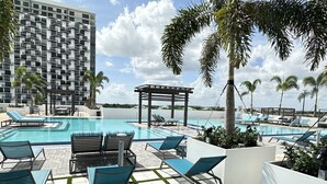 A rooftop pool area with lounge chairs, a pergola, and palm trees. - Walk to Downtown Doral / Resort Pool Free Parking (Doral)