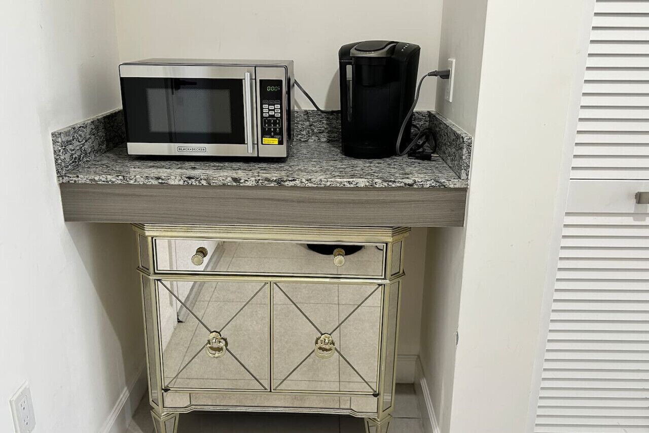 Une petite cuisine équipée d’un four à micro-ondes, d’une machine à café et d’un petit placard.