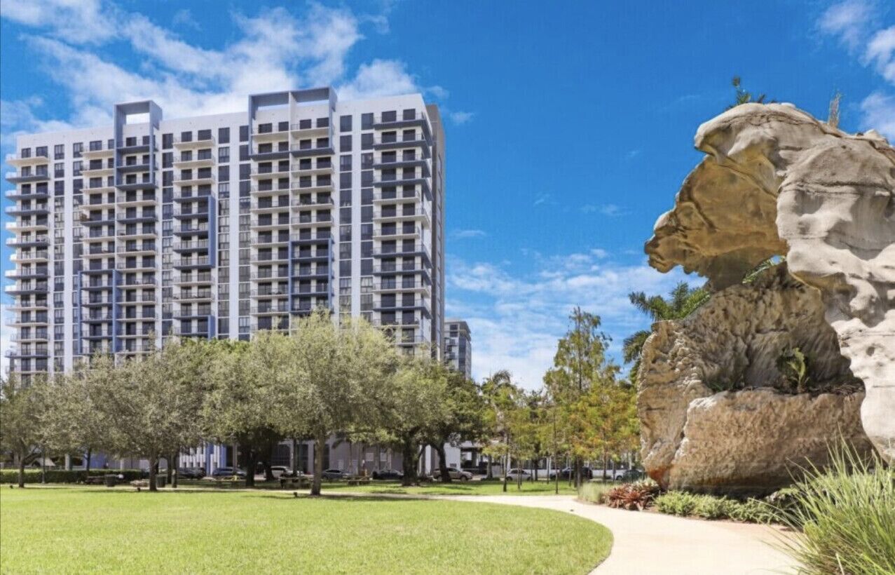 A modern high-rise building with a clear sky and a large rock formation in the foreground.