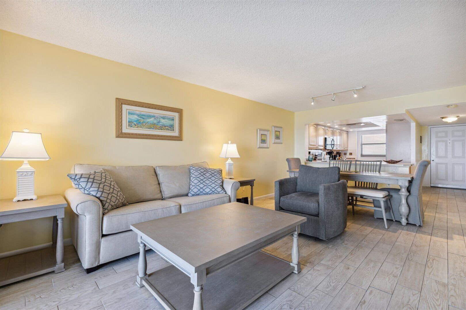 A living room with a sofa, armchairs, a coffee table, and a dining area with a table and chairs.