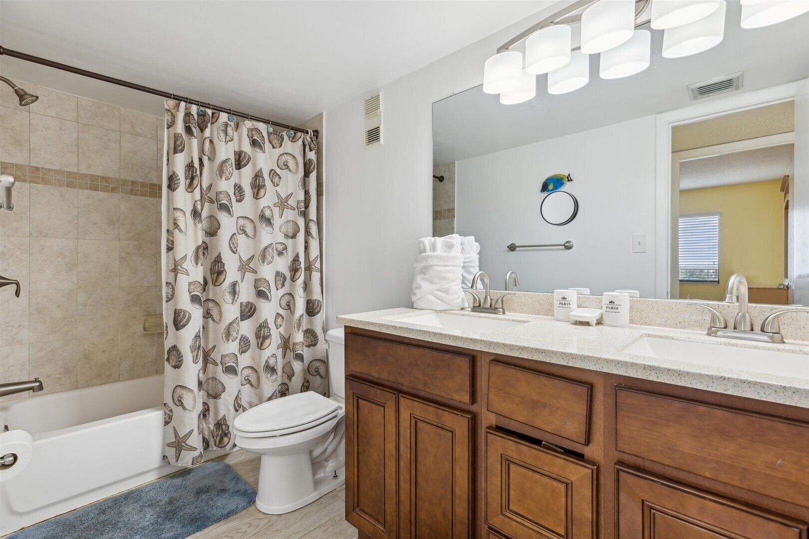 A bathroom with a shower, toilet, and vanity with a mirror and towel rack.