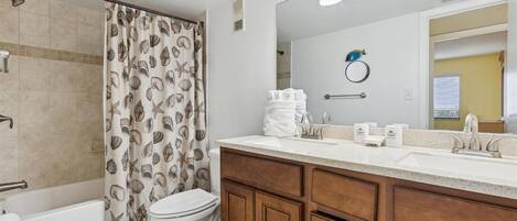 A bathroom with a shower, toilet, and vanity with a mirror and towel rack.