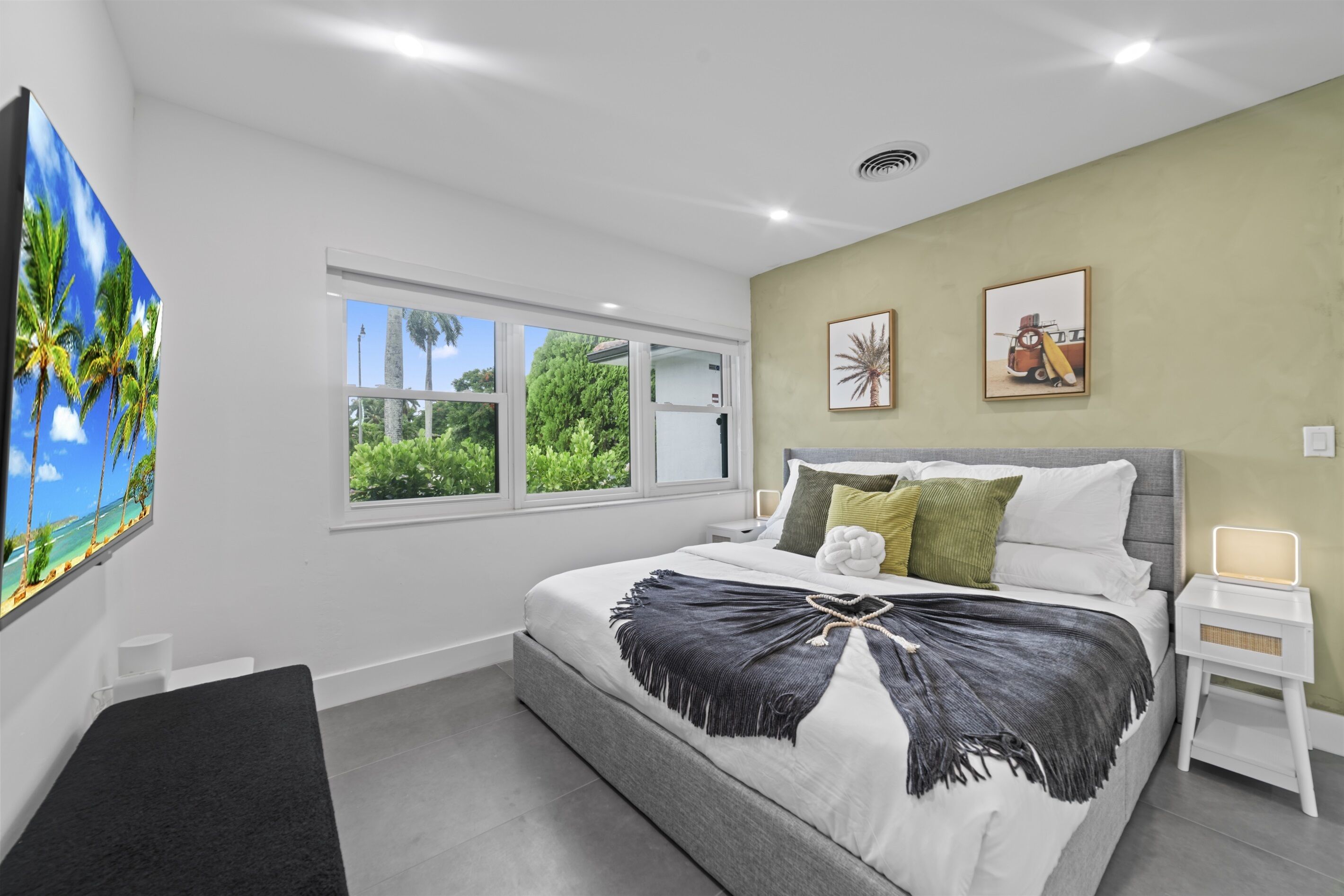 Une chambre à coucher moderne avec un grand lit, une fenêtre donnant sur un paysage verdoyant et deux tableaux encadrés accrochés au mur.
