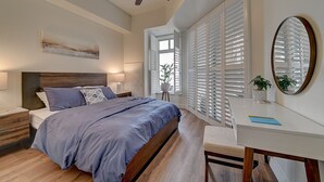 Un dormitorio con cama, mesita de noche, escritorio, silla y ventilador de techo.