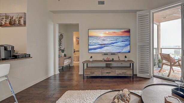 Una sala de estar moderna con un televisor de pantalla plana, un rincón para café y vistas al exterior.