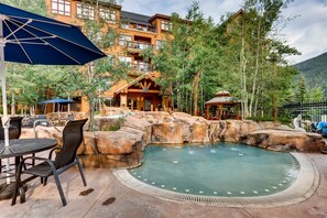 A pool area with a hot tub, surrounded by wooden structures and a mountainous backdrop. - 1 Bedroom Condo (Keystone)