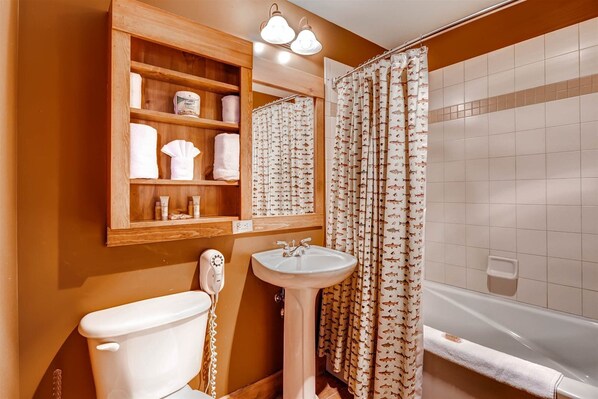 A bathroom with a wooden vanity, a toilet, a sink, and a bathtub.