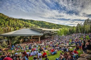 An outdoor amphitheater with a stage and seating area surrounded by a forested hillside. - Guest Room, One King (Vail)