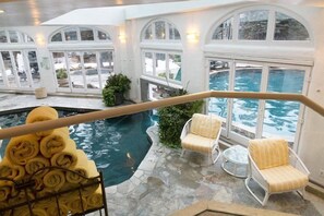 An indoor pool area with a view of the outside, stone flooring, and white wicker chairs. - Guest Room, One King (Vail)