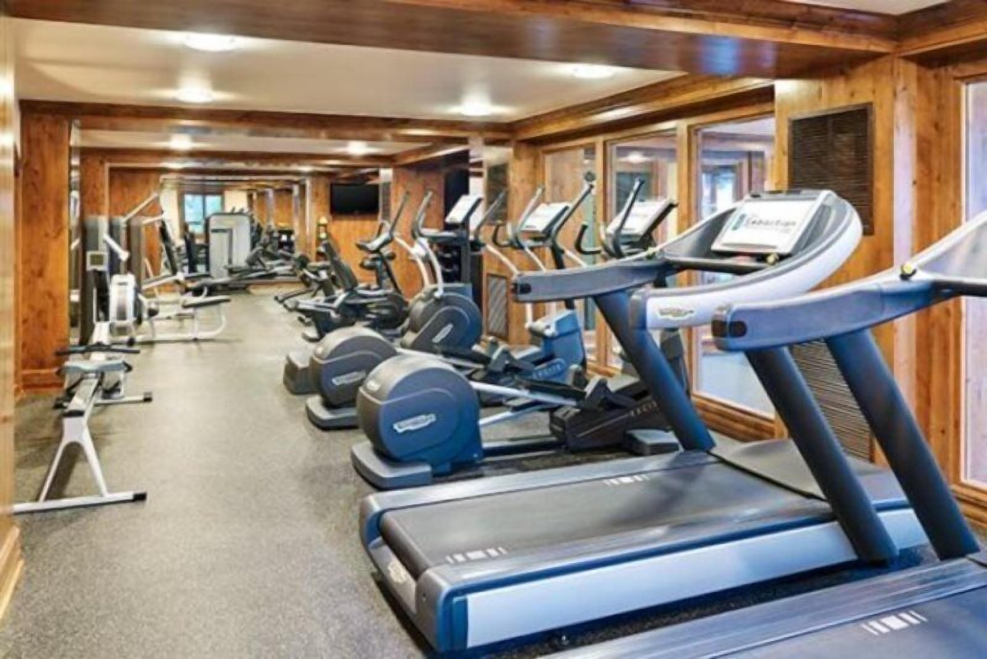 Une salle de sport équipée de plusieurs tapis de course et d'appareils de musculation.