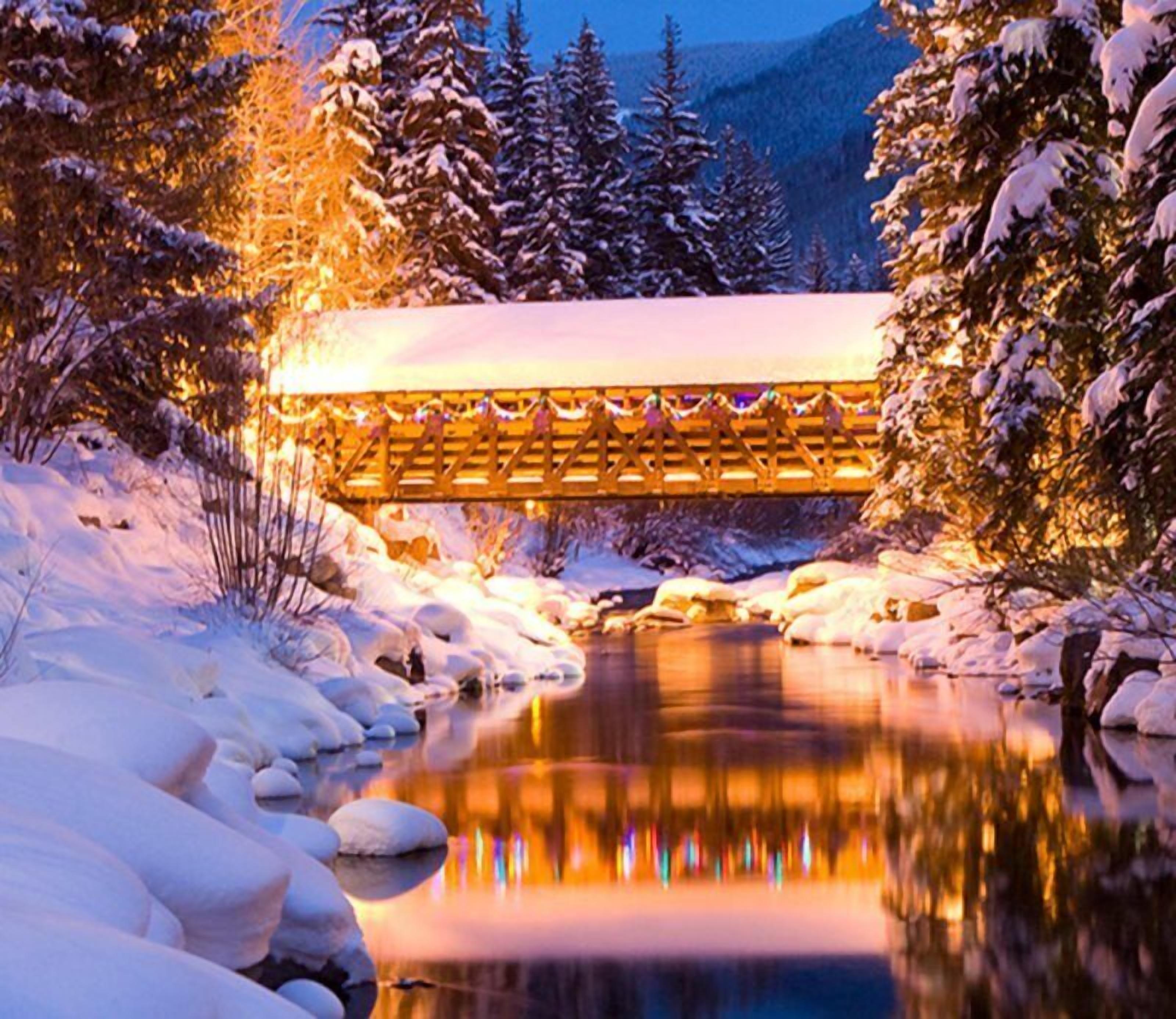 Eine schneebedeckte Brücke mit einem hölzernen Geländer und einem Weg, der dorthin führt.