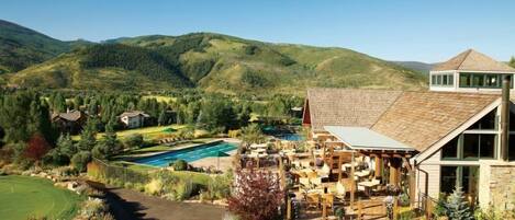 A resort with a pool, outdoor seating, and a view of the surrounding hills.