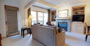 A living room with a sofa, a fireplace, a television, and a bookshelf. - 1 Bedroom (Vail)