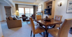 A spacious living room with a sofa set, a dining table with chairs, a fireplace, and a television. - 1 Bedroom (Vail)