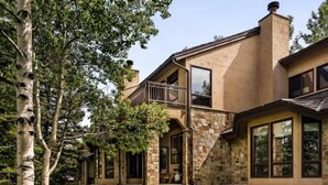 A two-story house with a stone facade, large windows, and a covered patio area. - 3 Bedroom Residence (Snowmass Village)