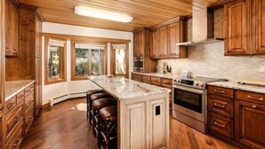 A kitchen with wooden cabinets, a central island, and a large window. - 3 Bedroom Residence (Snowmass Village)