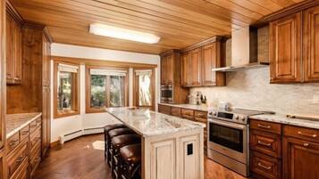 A kitchen with wooden cabinets, a central island, and a large window.