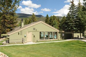 A single-story building with a sloped roof, large windows, and a small attached garage. - 2 Bedroom Condo (Keystone)