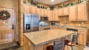 A kitchen with wooden cabinets, a stainless steel refrigerator, a microwave, a stove, and a sink. - 1 Bedroom Condo (Keystone)
