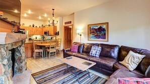 Una sala de estar acogedora con chimenea de piedra, un sofá de cuero y un comedor con muebles de madera.