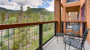 A balcony with a view of a forested mountain range, equipped with a table and chairs. - 3 Bedroom Condo (Keystone)