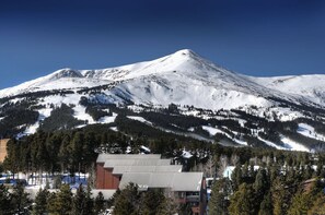 A snow-covered mountain with a ski resort in the foreground, featuring buildings with sloped roofs and a clear sky. - 3 Bedroom Condo (Breckenridge)