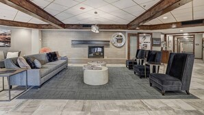 Un hall espacioso con un sofá gris, sillones, una mesa de centro y una chimenea.