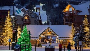 A snow-covered village with traditional wooden buildings, a Christmas tree, and a ski lift in the background. - 2 Bedroom Condo (Keystone)