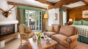 A cozy living room with a fireplace, leather sofa, and a dining table set with flowers. - 2 Bedroom (Vail)