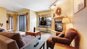 Una sala de estar con chimenea, televisor y un ventanal grande.