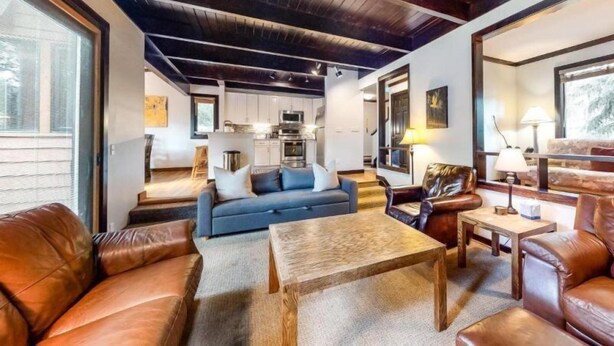 A spacious living area with leather sofas, a wooden coffee table, and a kitchen in the background. - 3 Bedroom Condo (Keystone)