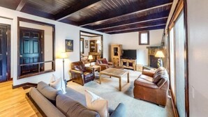 A spacious living room with a high ceiling, wooden beams, a fireplace, and a television. - 3 Bedroom Condo (Keystone)