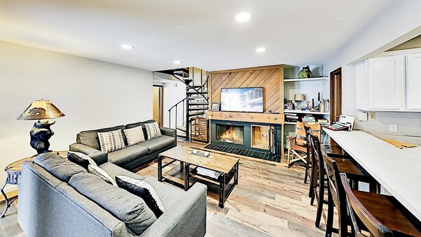 A modern living room with a fireplace, a sofa set, a coffee table, and a dining area with bar stools. - 3 Bedroom Condo (Keystone)