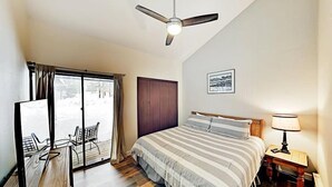 A bedroom with a bed, a desk, a chair, a ceiling fan, and a window with curtains. - 3 Bedroom Condo (Keystone)