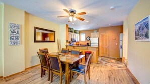 A dining area with a wooden table and chairs, a ceiling fan, and a kitchen in the background. - 2 Bedroom Condo (Keystone)